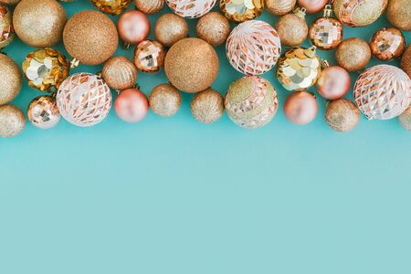 Frame made with golden Christmas tree balls on pale blue background with glitters. Festive concept, top view.の写真素材