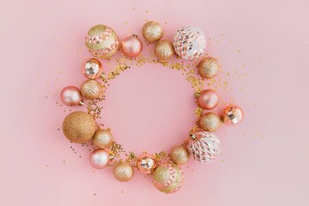 Frame made with glitters and golden Christmas tree balls on pale pink background. Festive concept, top view.の写真素材
