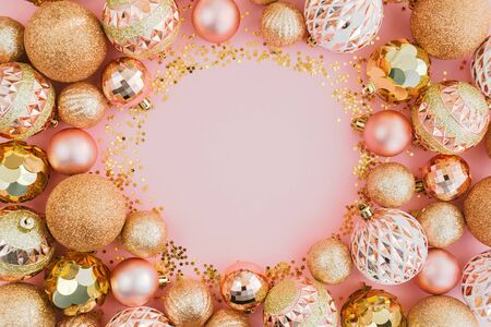 Frame made with glitters and golden Christmas tree balls on pale pink background. Festive concept, top view.の写真素材