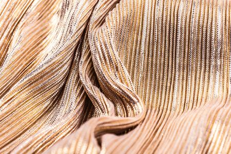 Golden shiny striped fabric, abstract background. Close-up, waves.の写真素材