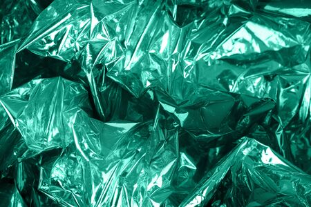 Crumpled toned mint green wrapping paper with shiny effect. Close up.