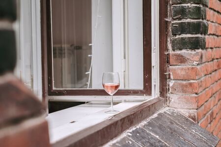 Glass of rose wine is standing on windowsill. Lifestyle view.の写真素材