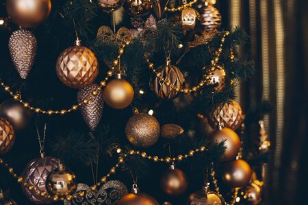 Fir branch with golden balls and festive lights on the dark background with sparkles.の写真素材