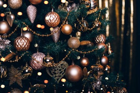 Fir branch with golden balls and festive lights on the dark background with sparkles.の写真素材
