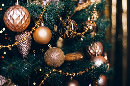 Fir branch with golden balls and festive lights on the dark background with sparkles.の写真素材