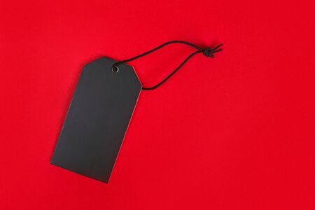 Blank black tag on red background with copy space.の写真素材