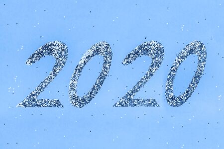 Golden sparkles shaped 2020 toned blue background. Flat lay style.の写真素材