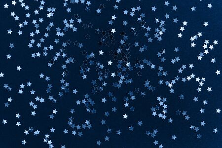 Golden star glitter confetti on dark blue background. Festive holiday background. Celebration concept. Top view, flat lay.の写真素材