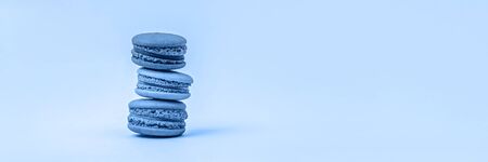 Banner with three macaroons toned on blue background with copy space. Tasty macaroons tower, 2020.