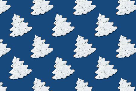 Pattern made of fir tree shaped ginger cookies on blue background. Christmas concept, 2020. Top view, flat lay.の写真素材