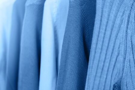 Row of knitted warm sweaters onhangers toned blue color, 2020.の写真素材