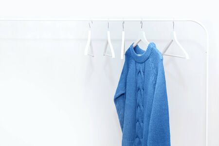 One classic blue knitted warm sweater on white hanger and many empty hangers. Shopping and sale concept.の写真素材