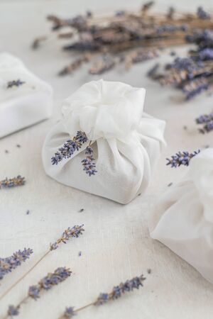 Present wrapped with white furoshiki fabric and decorated with lavender flowers. Eco friendly gift, zero waste concept.の写真素材