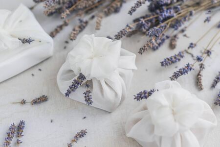 Present wrapped with white furoshiki fabric and decorated with lavender flowers. Eco friendly gift, zero waste concept.の写真素材