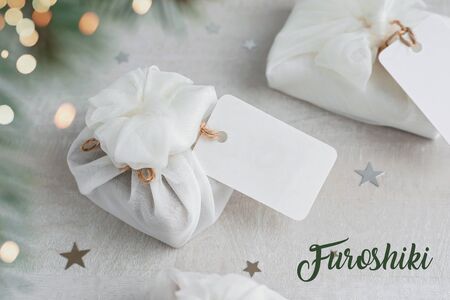 Christmas present wrapped with white furoshiki fabric with labels. Eco friendly gift, zero waste concept.の写真素材