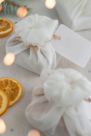 Christmas presents wrapped with white furoshiki fabric, labels and dried orange slices. Eco friendly gift, zero waste concept.の写真素材