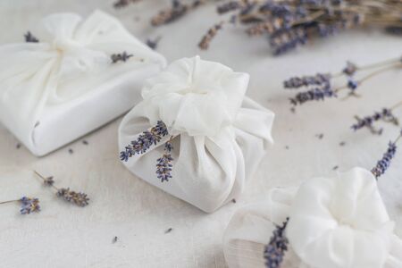 Present wrapped with white furoshiki fabric and decorated with lavender flowers. Eco friendly gift, zero waste concept.の写真素材