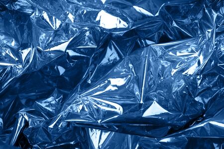 Crumpled silver paper with golographic and chameleon effect toned blue color. Close up.の写真素材