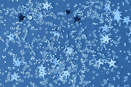 Delicate glitter star confetti on blue background. Creative and moody color of the picture, 2020.の写真素材