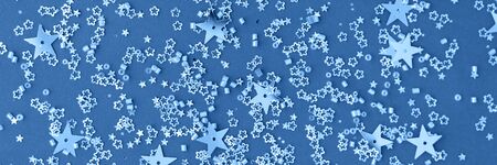 Banner made with delicate glitter star confetti on blue background. Creative and moody color of the picture. Top view.の写真素材