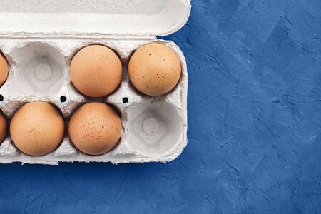 Eggs in a tray on classic blue concret background, top view, space for text.の写真素材