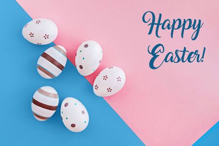 Eggs decorated with stripes and flowers on pink and blue background, Easter concept with text.の写真素材