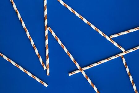 Background made of coctail straws with golden stripes on blue color. Top view.の写真素材