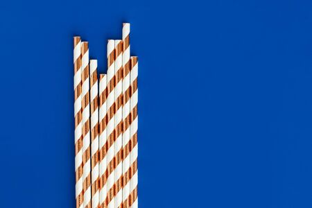 Background made of coctail straws with golden stripes on blue color. Top view.の写真素材