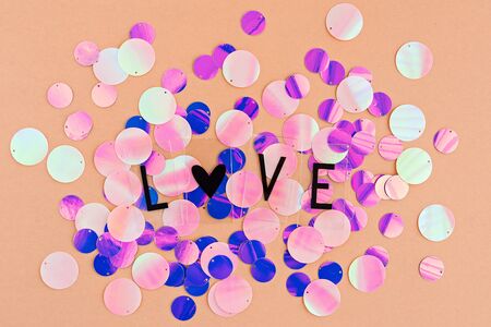 Background with shiny pink, purple and holographic sequins with word love, abstract background. Valentine's day card.の写真素材