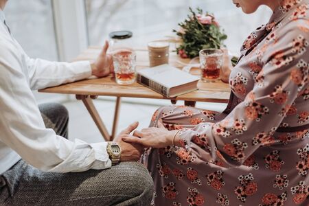 A romantic couple holding hands with wedding rings.