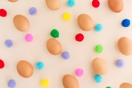 Easter eggs pattern with colorful pompons on beige background. Top view, flatlay.の写真素材