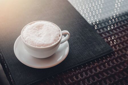 White big cup of cappuccino with foam on black table. Morning coffee concept with stylish toning and place for text.の写真素材