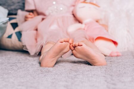 Cute little childss bare feet lying on warm knitted blanket with soft toy. Cozy time at home, lifestyle.の写真素材