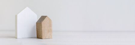 White wooden toy house on white pastel background with words stay at home. Quarantine and home stay...