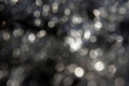 Abstract defocused black background with delicate white glitter bokeh. Blurred.の写真素材