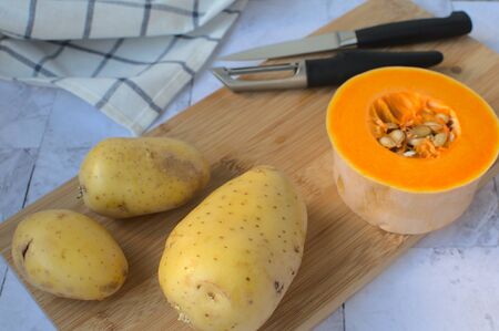 close-up potatoes next to piece of pumpkin on wooden table ..の写真素材