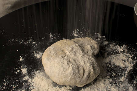 Close up of flour falling on pizza dough ready to knead.の写真素材