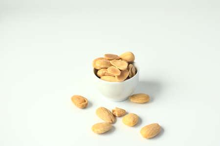Small white bowl with almonds, more almonds on a table in high key pictureの写真素材