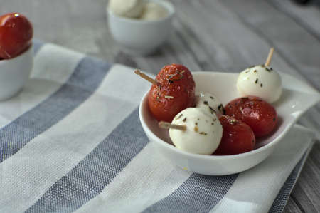 Small bowl with three units of cherry tomatoes snack with mozzarella cheese, at the bottom another...