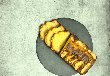 Close up of apple sponge with pine nuts on a gray stone tray, on a stone base