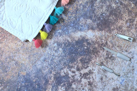 Manicure set consisting of cuticle pusher, nail clipper and file on one side and a white towel with colored tassels, on a background with a rusty look.の写真素材