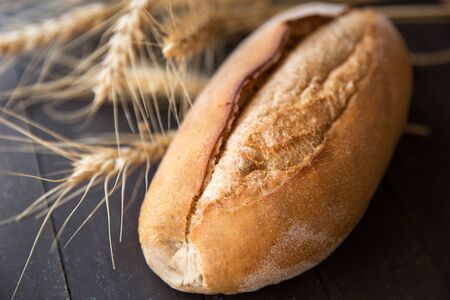 fresh bread with wheat ears on dark boardの写真素材