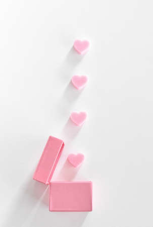 Pink hearts falling in same color gift box. Creative Minimal concept on white background. Love motives for Valentine's day. Flat lay.の写真素材