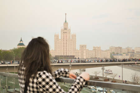 Girl on the bridge watching over the city of Moscow. View on tall white building.の写真素材