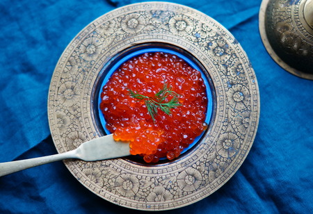 red caviar in vintage metal bowl on a blue background. Top viewの写真素材