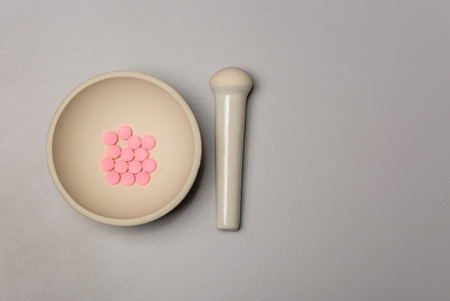 Medical mortar and pink pills on a gray backgroundの写真素材