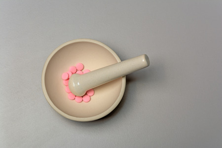 Medical mortar and pink pills on a gray backgroundの写真素材