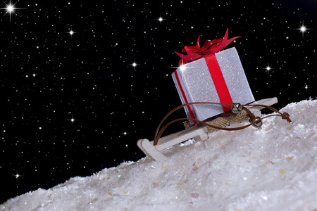 Christmas gift on sledge. Night, snowfall