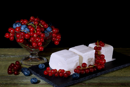 Ice cream with red currant berries. Vase with berries and cream ice cream on an old wooden table....