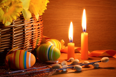 Easter still life with candles. Candles, Easter eggs and a basket with narcissuses.の写真素材